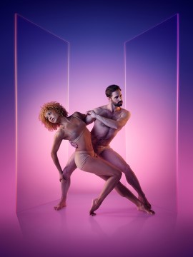 Les danseurs des Grands Ballets Canadiens Vanesa G.-R. Montoya et Raphaël Bouchard dans une pose artistique sur fond bleu et rose, pour le spectacle Ultraviolet
